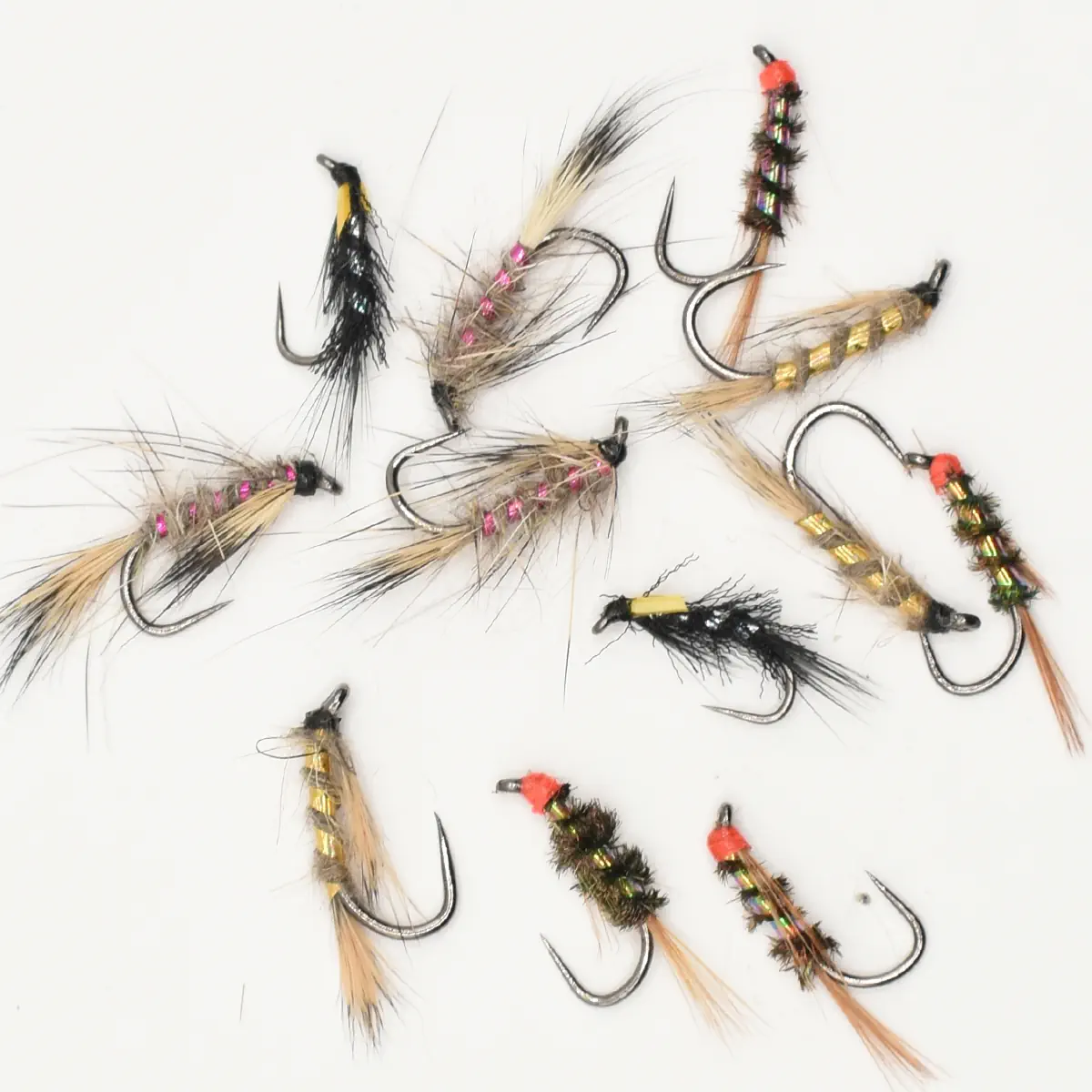 Assorted fishing flies with colorful bodies and feathers scattered on a white background.
