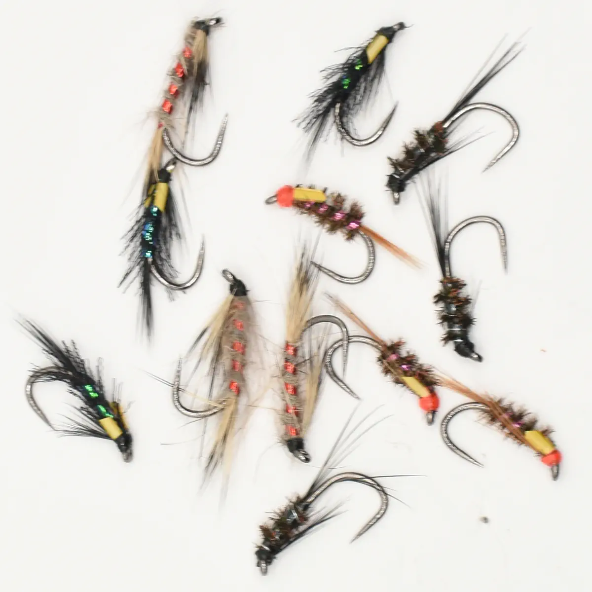 Assorted fishing flies with colorful beads and feathers scattered on a white background (fly patterns for fishing).