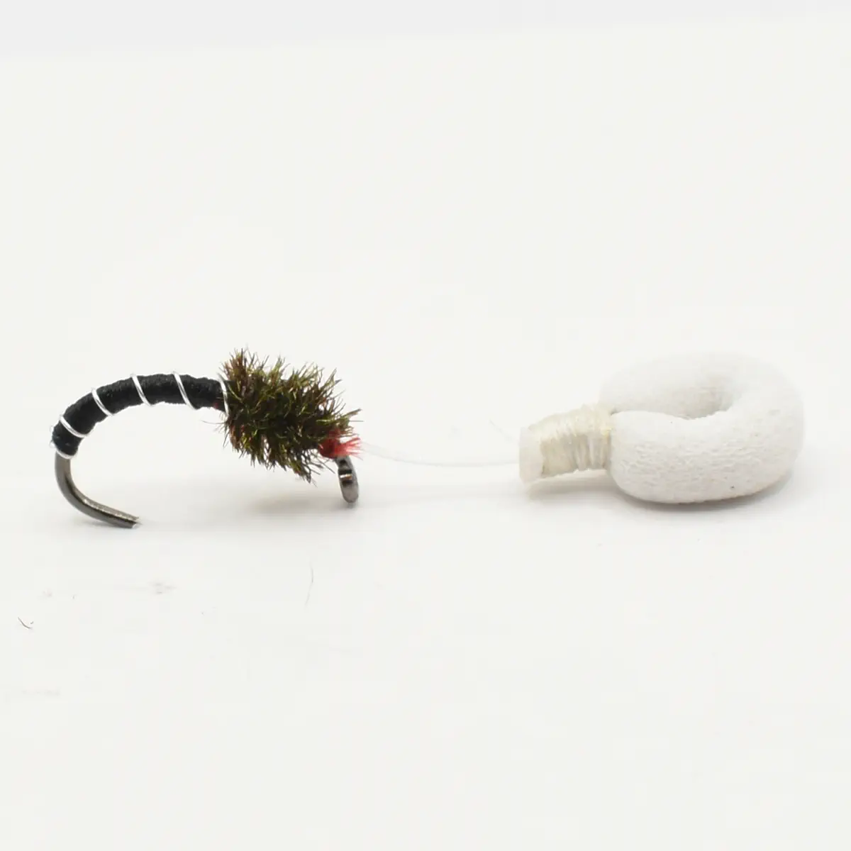 Close-up of a fishing fly lure tied to a curved hook, connected by a thin line to a white foam strike indicator or bobber.