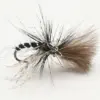 Close-up of a dry-fly fishing lure with a black body and brown-tan feather hackle on a curved hook surface, set against a light background.