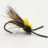 Close-up of a fishing fly lure with a black hook, brown feather hackle, and two yellow foam beads on the body.