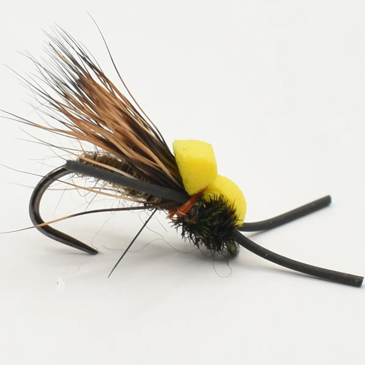 Close-up of a fishing fly lure with a black hook, brown feather hackle, and two yellow foam beads on the body.